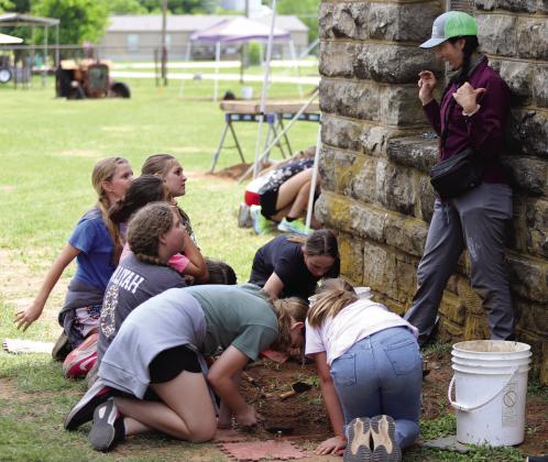 Briana Smith, Project Archeologist for Horizon Environmental Services, instructs Archer City 5th grade students on proper procedures for using a trowel to uncover artifacts. Photo/Nathan Lawson