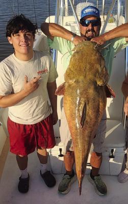 William Maxwell (left) and Brandon Brown poses with a record breaking 65.6 pound flathead catfish that Maxweel reeled in on Aug. 28. Courtesy photo