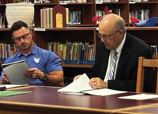 Ted Neeb (right), with Freemon, Shapard and Story presents the Windthorst ISD school board its 24-25 financial audit as school board member JD Steinberger (left) looks on in the Howard Neeb Library. Photo/Callie Lawson