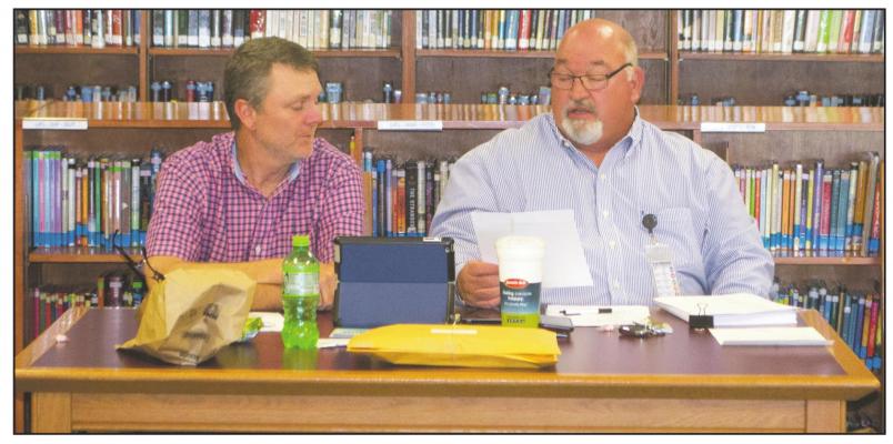 Windthorst ISD superintendet Lonnie Hise (right) reads off the details of the depository contract with Pilgrim Bank as school board president Chad Steinberger (left) listens on during the WISD school board meeting Monday, April 19, in Howard Neeb Library. Photo/Nathan Lawson