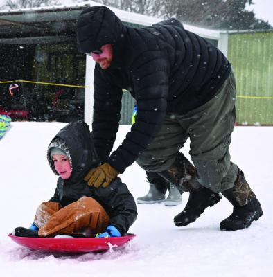 Winter Storm Fern brought nearly four inches of snow, sleet and ice starting on Friday, Jan. 23 through Jan. 25. The weather and road conditions caused many school, city and work closures throughout the county on Friday, Monday and Tuesday. TOP: Josh Winter pushes his son, Jaxson, down the hill at the Archer City Country Club on Saturday, Jan. 24. BOTTOM: TxDOT workers move snow off the road into a mound on a lot east of the Archer City Square on Monday, Jan. 26. Photos/Jenny Schroeder, Callie Lawson