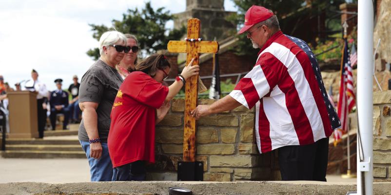 The family of Marine Sgt. Gary Johnston, who was killed in action in Iraq in 2007, places a cross on his memorial podium as part of Scotland-Windthorst Veterans of Foreign War Post 2676's Memorial Day service in Windthorst. Photo/Nathan Lawson