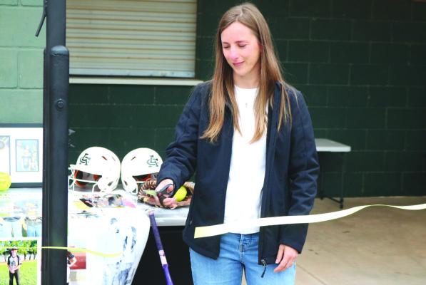 Candace Stephens cuts the ribbon at the Archer City ISD softball complex for the flagpole dedication to her late husband Cody Stephens on Friday, April 19. Stephens was one of the Lady Cats biggest fans and could be seen and heard at most games. Photo/Nathan Lawson
