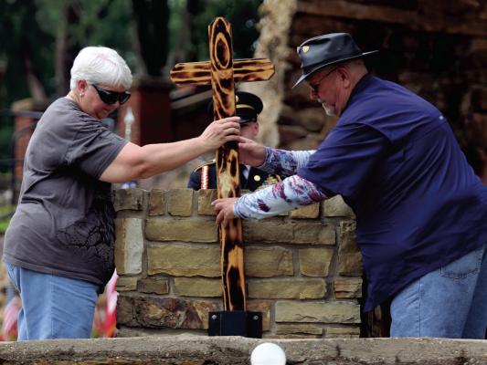 Angela and Nubbin Johnston place a cross at the memorial of their son, Marine Sgt. Gary S. Johnston, during Memorial Day ceremonies at the grotto of St. Mary's Catholic Church on Monday, May 26. Photo/Nathan Lawson
