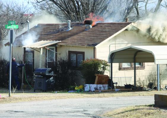 Archer County Sheriff Jack Curd cools off the front door of a structure fire in the 100 block of East Walnut before firefighters arrive on scene on Wednesday, Jan. 14. Photo/Nathan Lawson