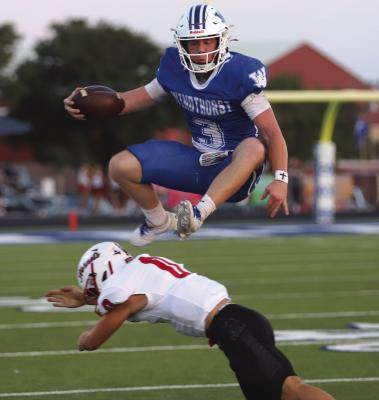 Windthorst Senior Quarterback Brock Belcher hurdles a Muenster Hornets defender in the Trojans 33-28 loss on Friday, Sept. 11, at Trojan Field. Photo/Rolando Medina