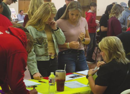 Holliday's Austin Linn (left), Sarah Cowan (middle) and Lybi Carlton (right) visit a booth at the "Welcome to the Real World," workshop on Thursday, April 14. Photo/Nathan Lawson