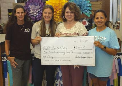 L-R: Amy Huseman, Archer City Elementary principal, Amanda Awakuni, librarian, Miriam Knobloch, Beta Sigma member and Vicky Lopez, Beta Sigma member, pose for a photo with a check presented to ACISD for spanish language books. Courtesy photo