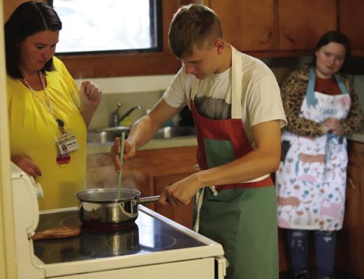 Students Jesse Berend (cooking) and Maddi Chatwell (back) learn life skills as Brooke Pope supervises. The students are part of ACISD's 18+ program for special needs students. Photo/Landon Davis