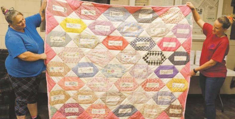 Archer Service Center staff members Leslie Lewis on the left and Kelli Howell on the right display the special quilt to be included in the upcoming online auction. Photo/Jerry Phillips