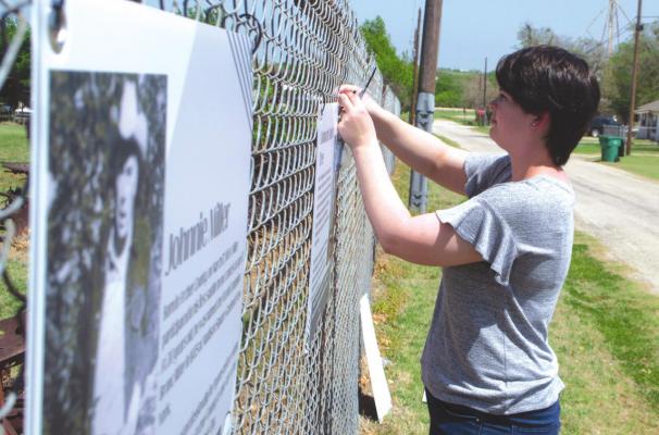 Archer County Museum and Arts Center Executvie Director Callie Lawson hangs the museums new fence exhibits outside the museum located at 203 E. Pecan in Archer City on Thursday, April 21. The exhibit will remain hanging while the building remains closed. Photo/Nathan Lawson